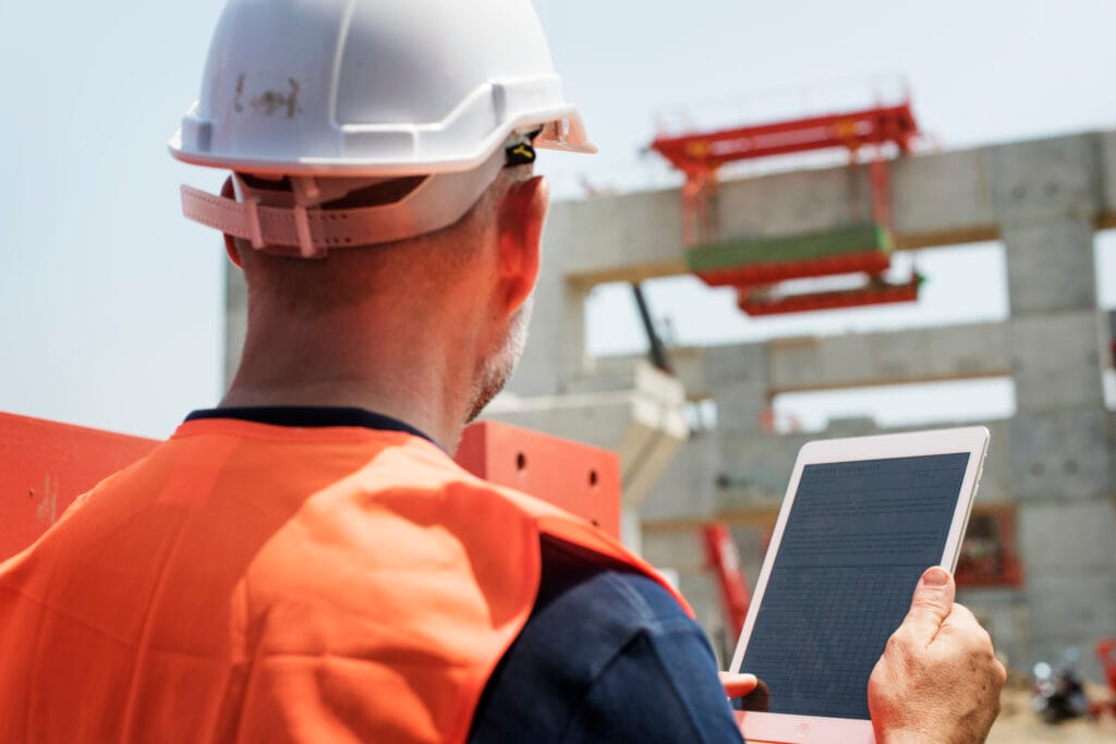 Expert immobilier effectuant un suivi de chantier avec une tablette